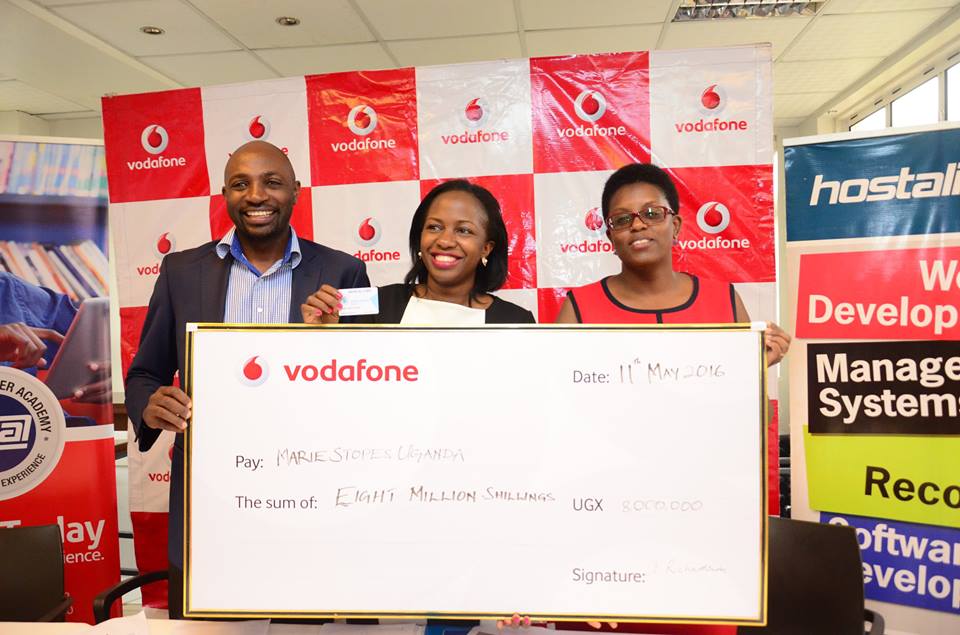 Dickson Mushabe- Regional Manager Hostalite Ltd and Faith N. Kyateka- Communications and External Relations manager Marie Stopes Uganda receive the shs8 million dummy cheque from Jackie Namara Rukare- Marketing Manager Vodafone Uganda for their joint partnership challenge dubbed "Hackathon" at the Vodafone head office.