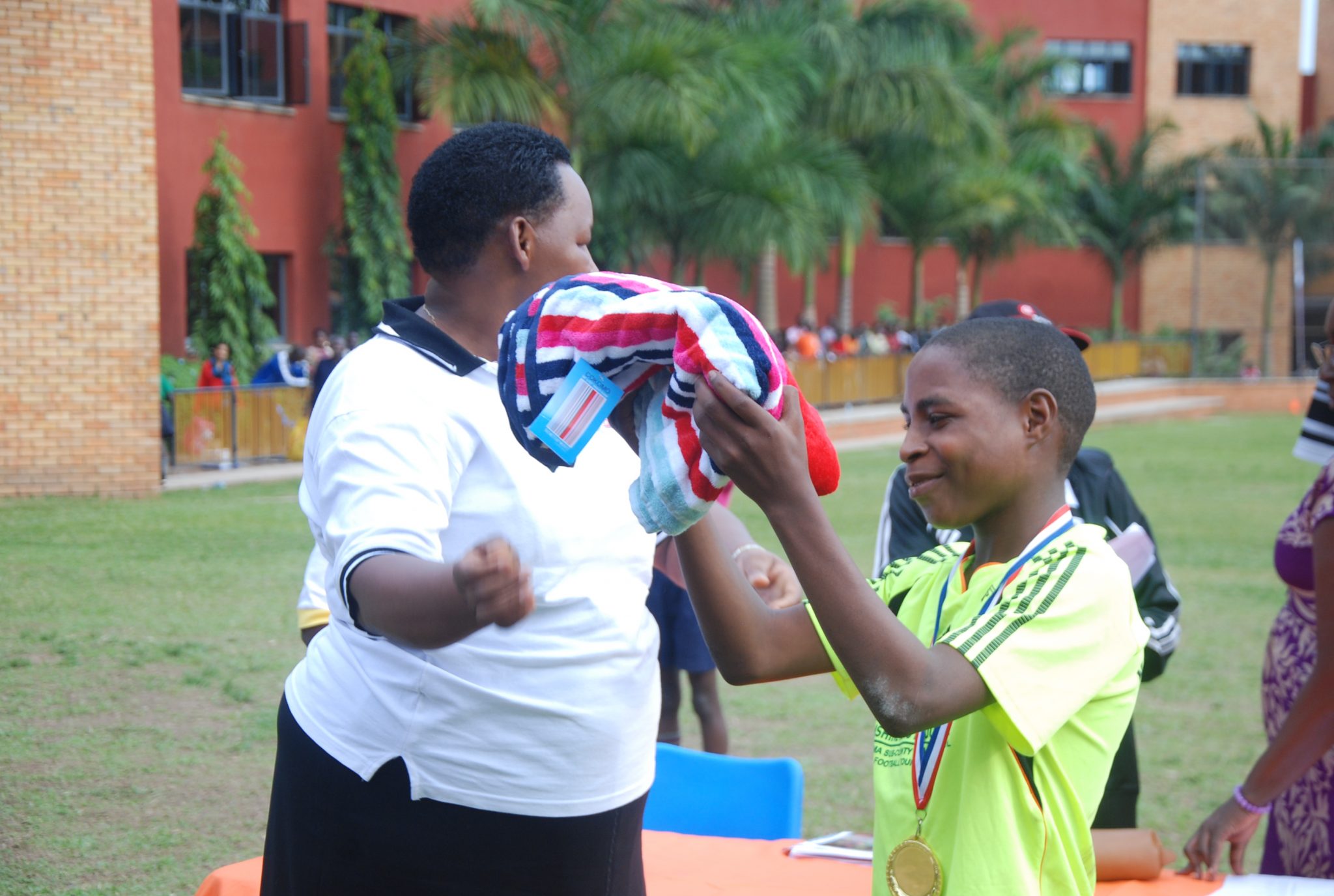 Gerald Kawoya of Muto Primary School receives a towel from Daphne Kato, the principal of Kampala Parents School.