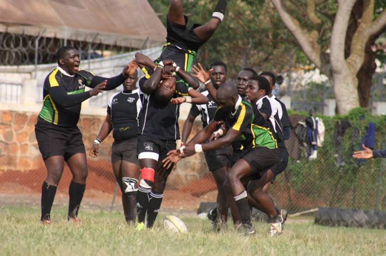 Rhinos' player (in black and green) being tackled by the Impis player (in black and white)