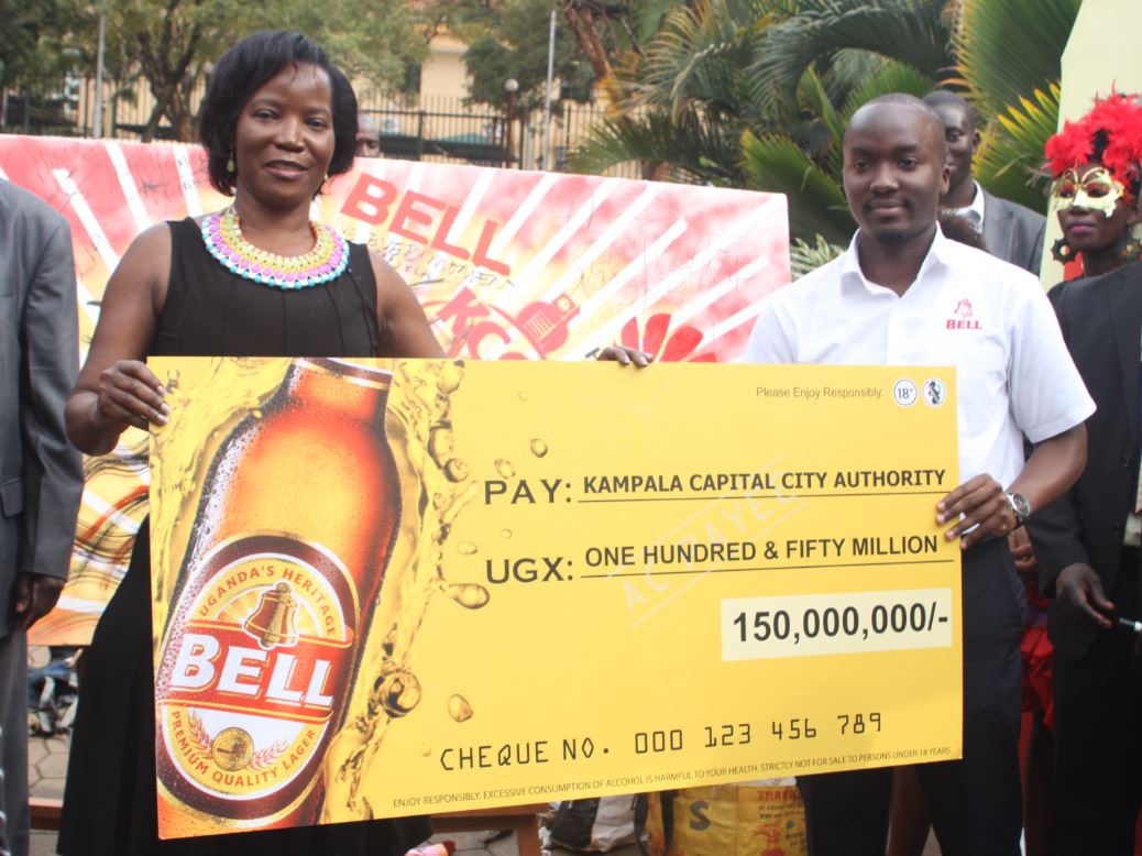 Jennifer Musisi, the Executive Director KCCA receives a cheque of UGX150m for sponsorship of the 2015 Kampala City Festival from Robert Nsibirwa, the Bell Lager Brand Manager