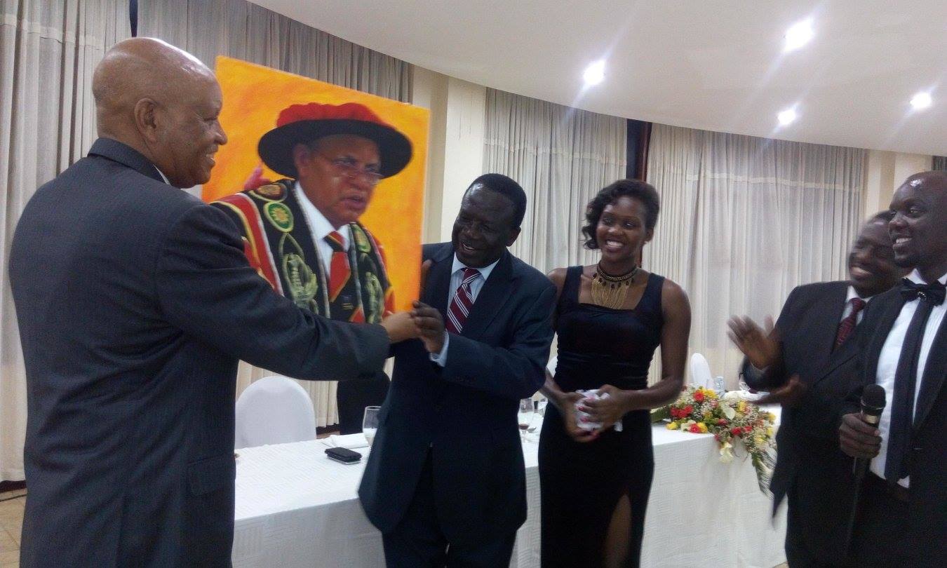 Mondo Kagonyera being presented with a portrait by Bala and his Vice, Phiona Nyamutooro. Looking on is the Chairperson of University Council, Eng. Wana Etyem.