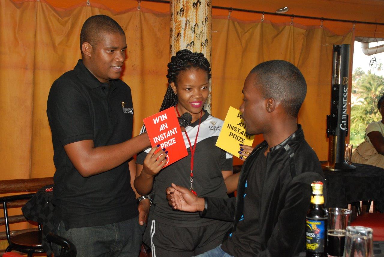 Andrew Kabuura (L) helps an usher book a Guinness consumer during a Guinness Get Booked activation. Six lucky Ugandans will be flown to the UK courtesy of Guinness.