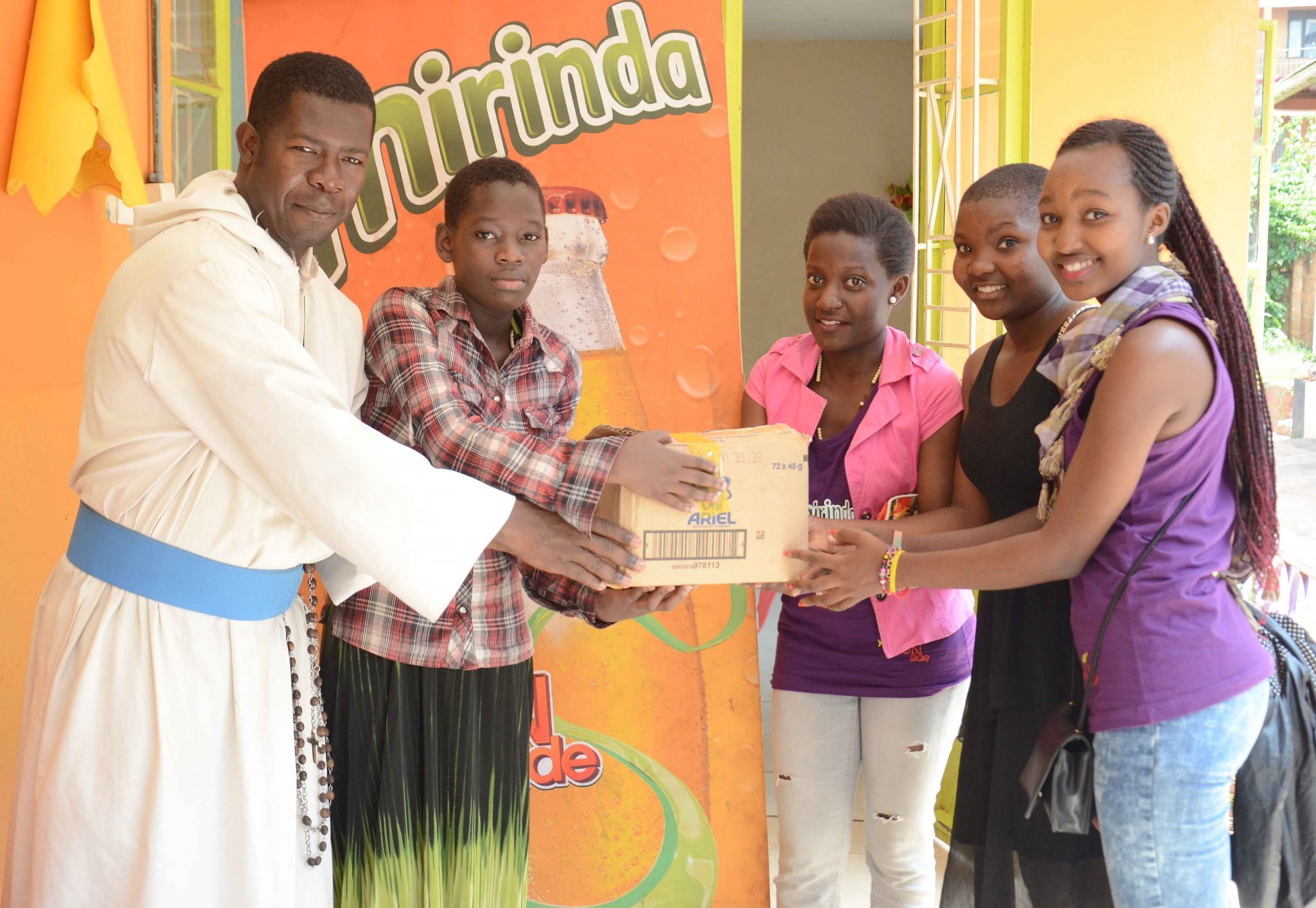 Reigning Mirinda Miss Teen- Vaneesa Nansoove (in pink) hands over toiletries and food supplies to the Missionaries of the Poor represented by brother Loubert