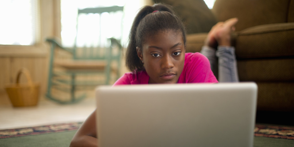 African American female teen on floor with laptop