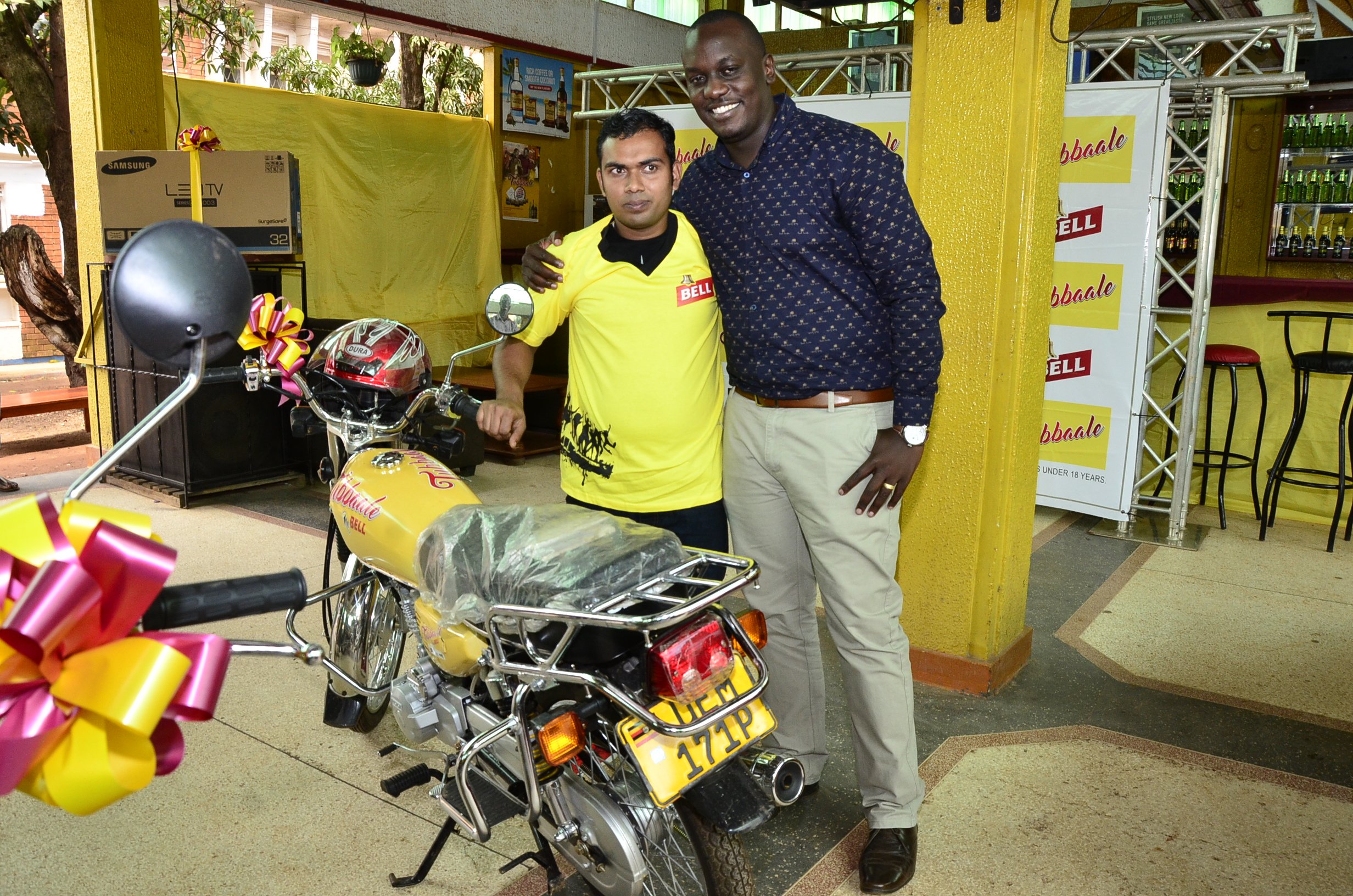 Brian Seruyiggo (R), Customer Marketing Manager-Bell Lager congratulates Ali Asjan (L), a motorcycle winner in the UBL Tubbaale promotion at UMA Showgrounds