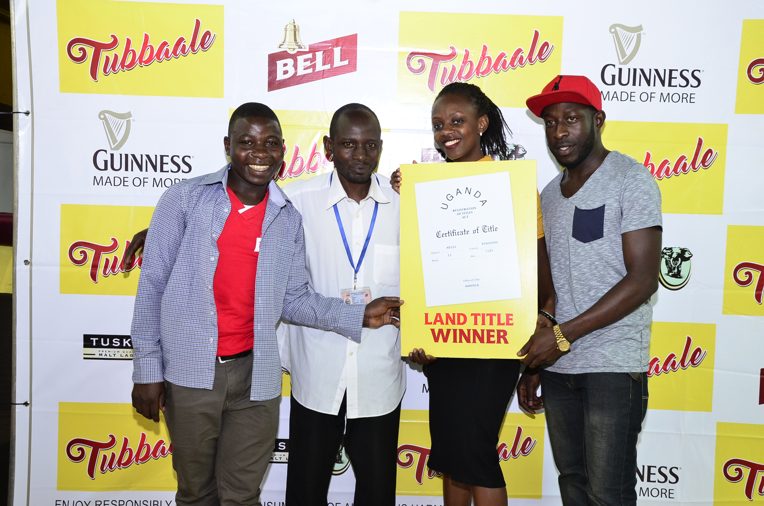  (L-R) Winners of land receive a dummy title. Makenya Stephen, Walusimbi Joseph, Cathy Twesigye, Guinness Activation Manager and Serunjogi Julius.