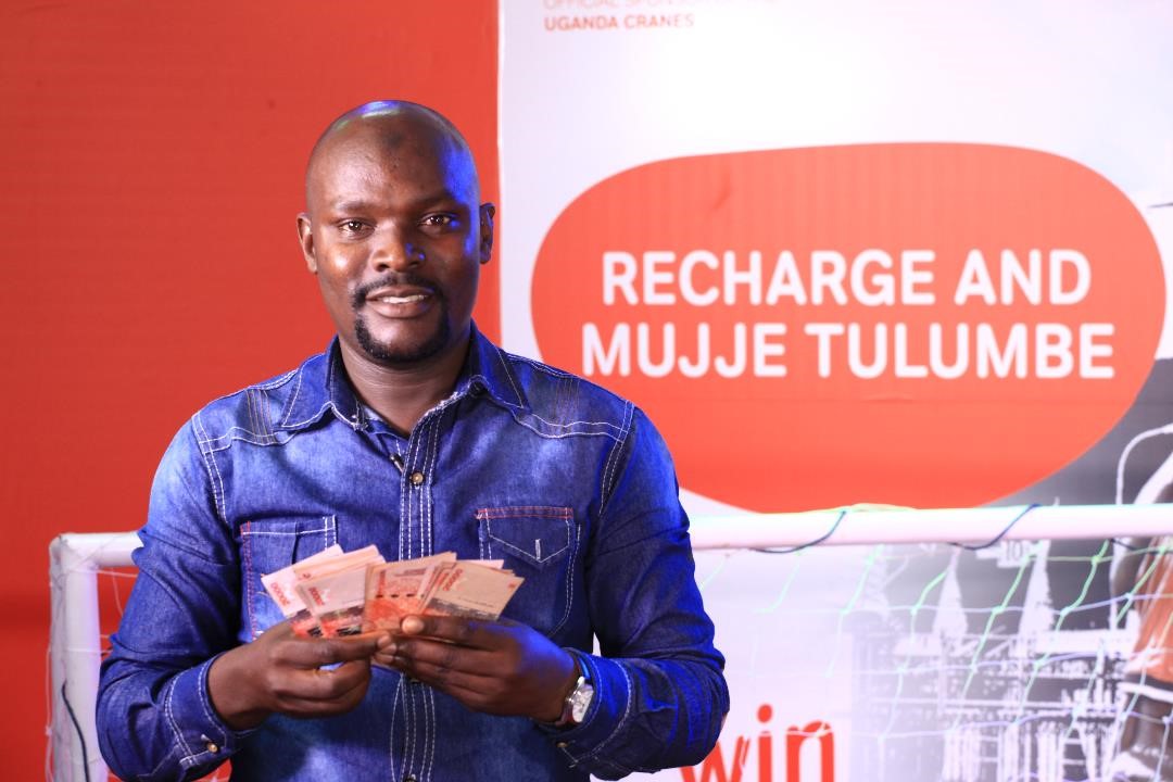 Mugumya Hassan, Business man from Katooke pose for a photo with his money he won in the Recharge Promotion.