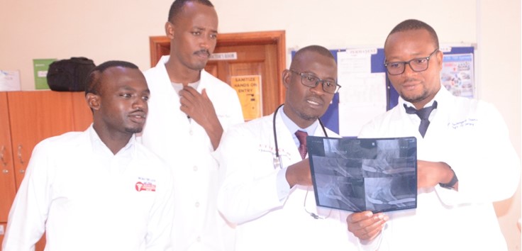 Dr. Mwesigwa and the residents examining an x-ray scan of one patients in the urology unit