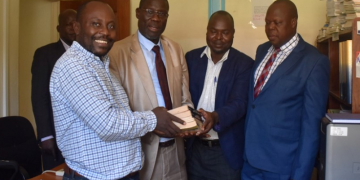 The UN team leader hands over the books to Vice Chancellor Gulu University as the Acting University Librarian and Deputy University Secretary look on